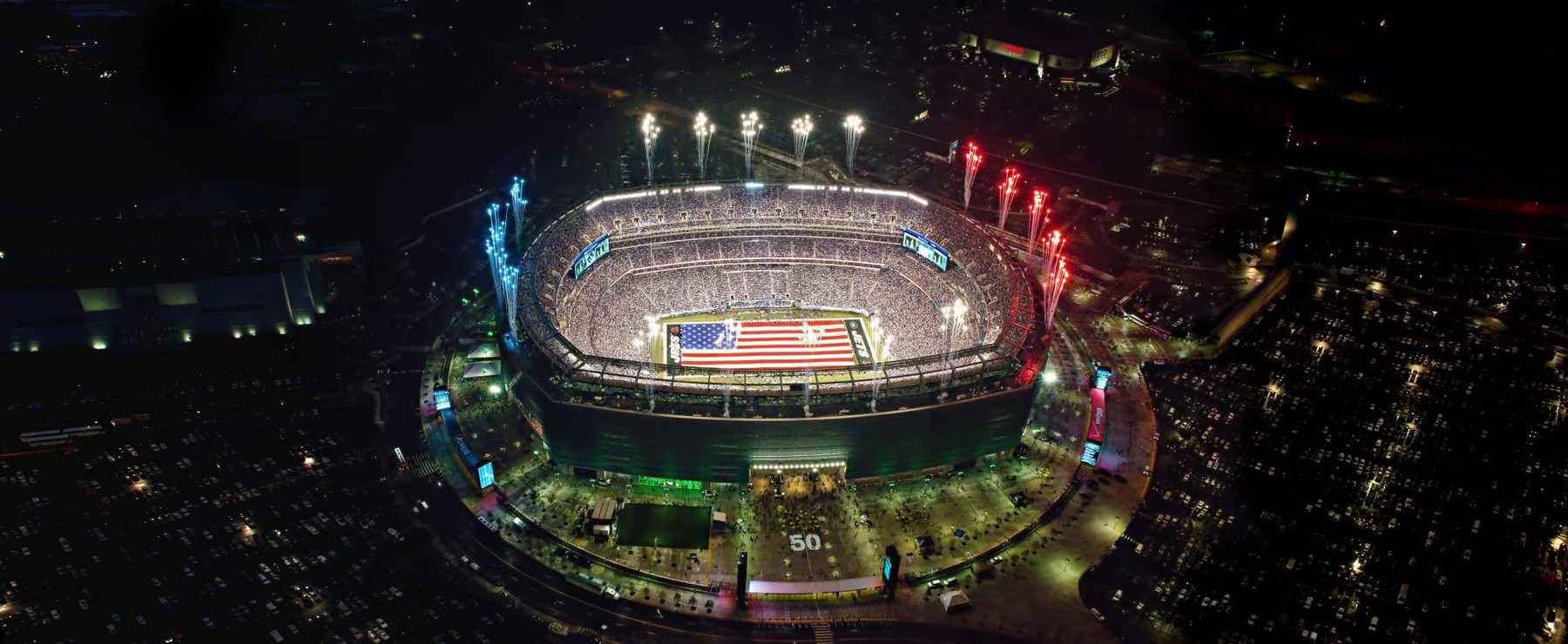 Aerial of the Jets stadium opening ringed with red, white and blue fireworks