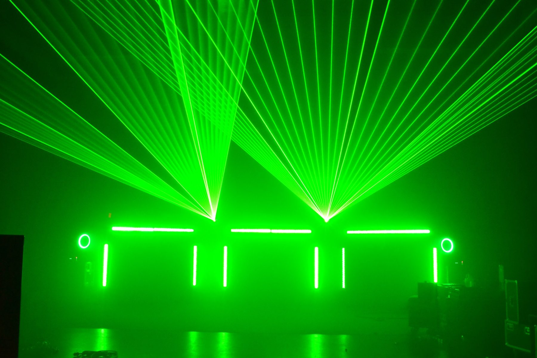 Two fans of green laser beams over glowing LED bars