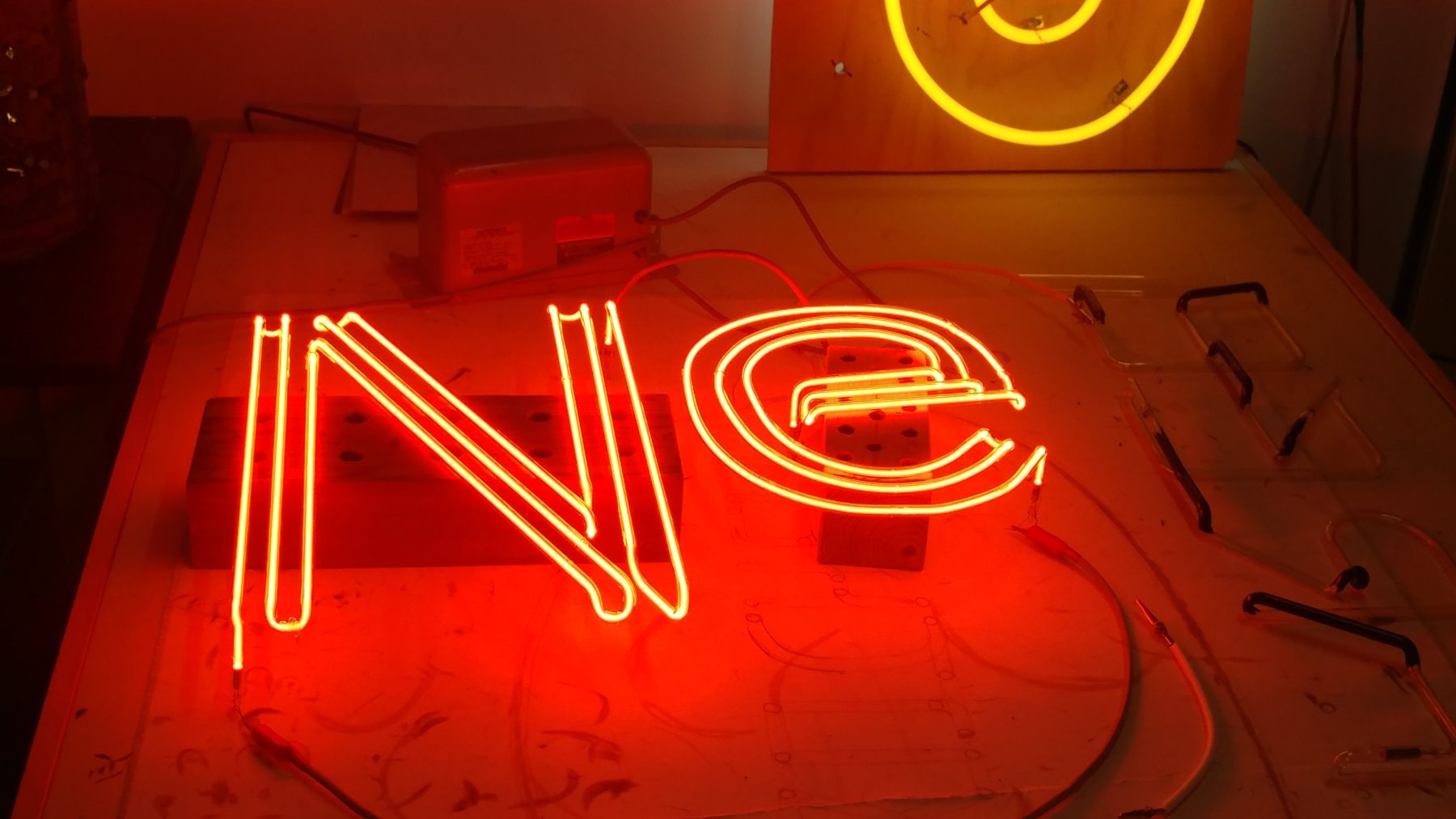 Glowing red neon letters on a workbench